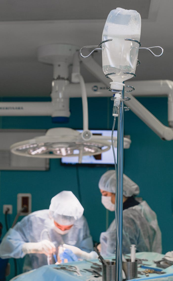 Medical professionals in surgical attire performing an operation in a sterile environment.